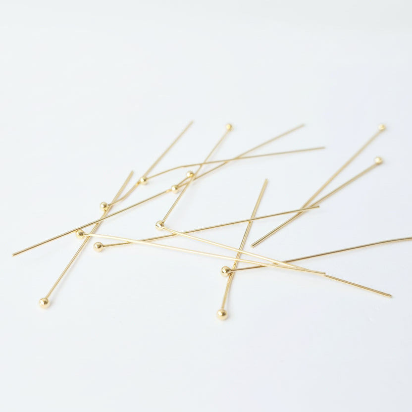 Gold headpins on a light blue background