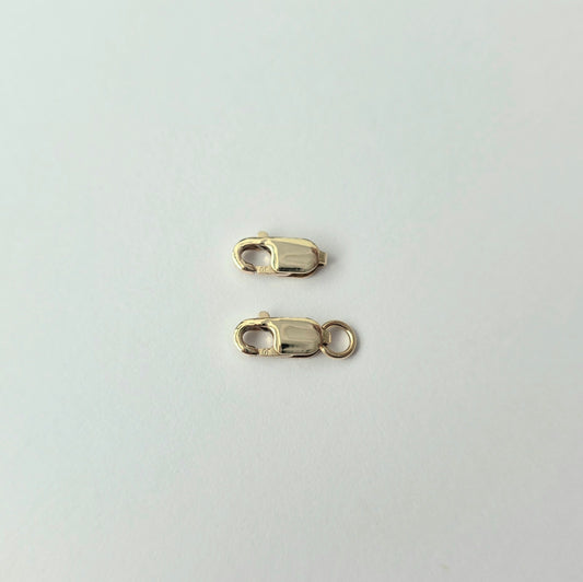 Two gold lobster clasps on a light gray background