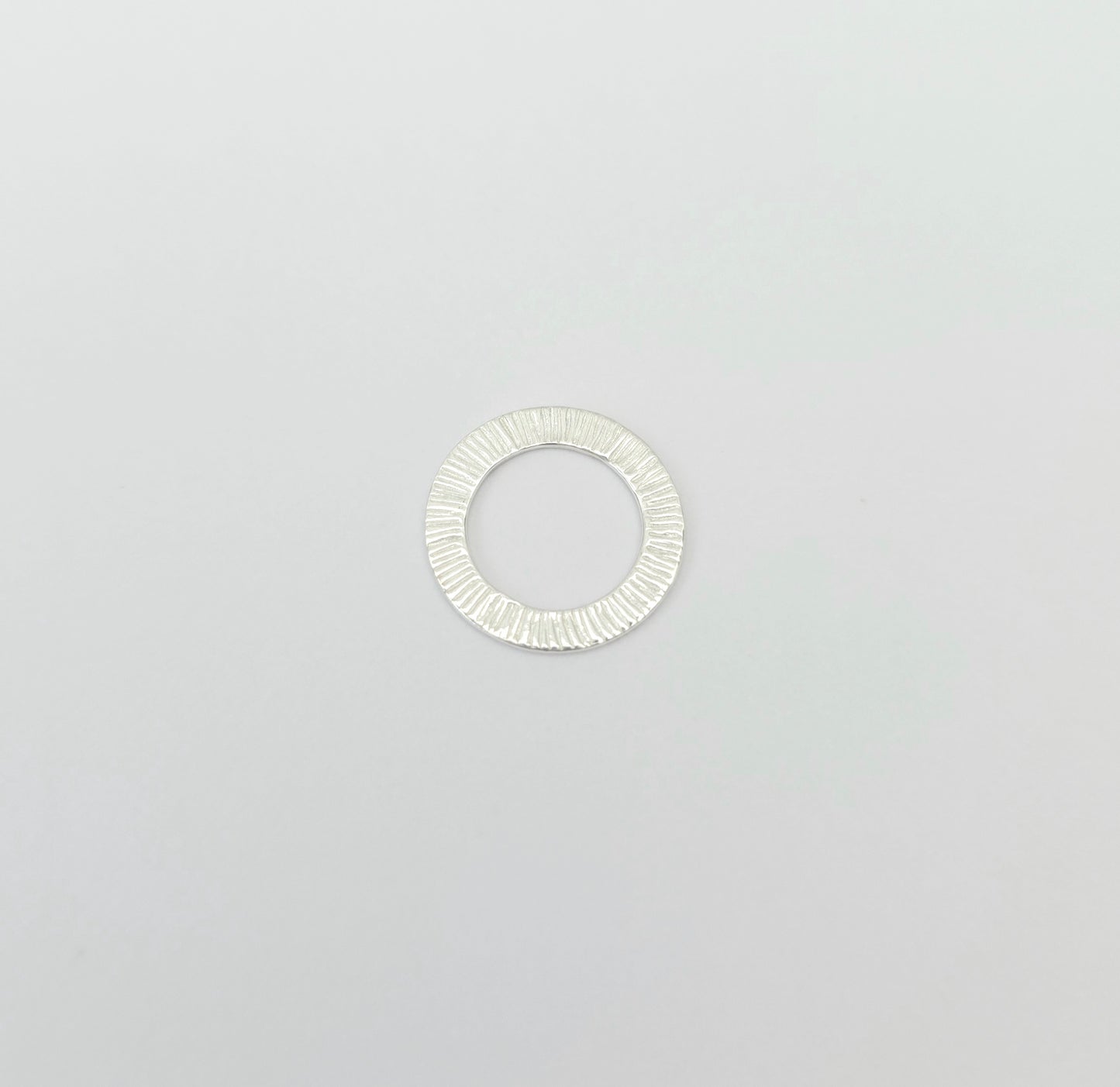 Silver ring with a textured band on a light gray background