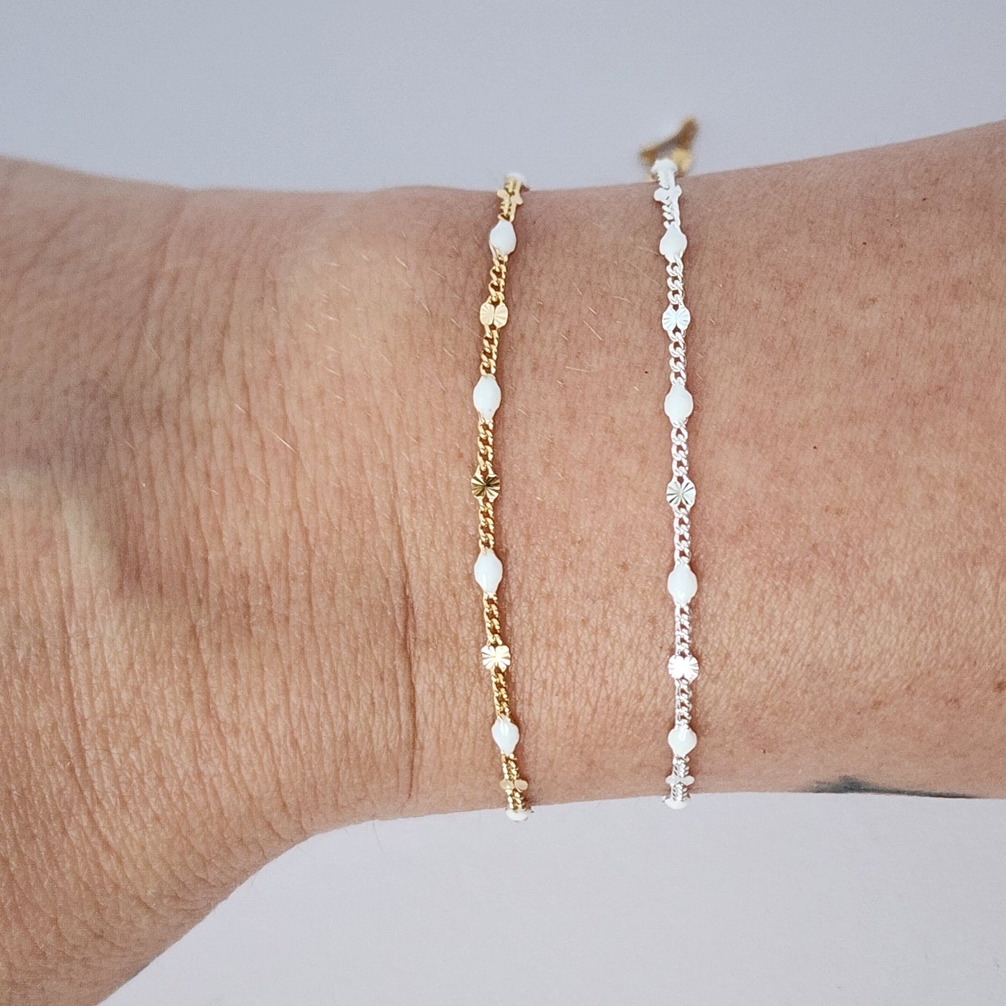Two gold anklets on a person's ankle against a light gray background