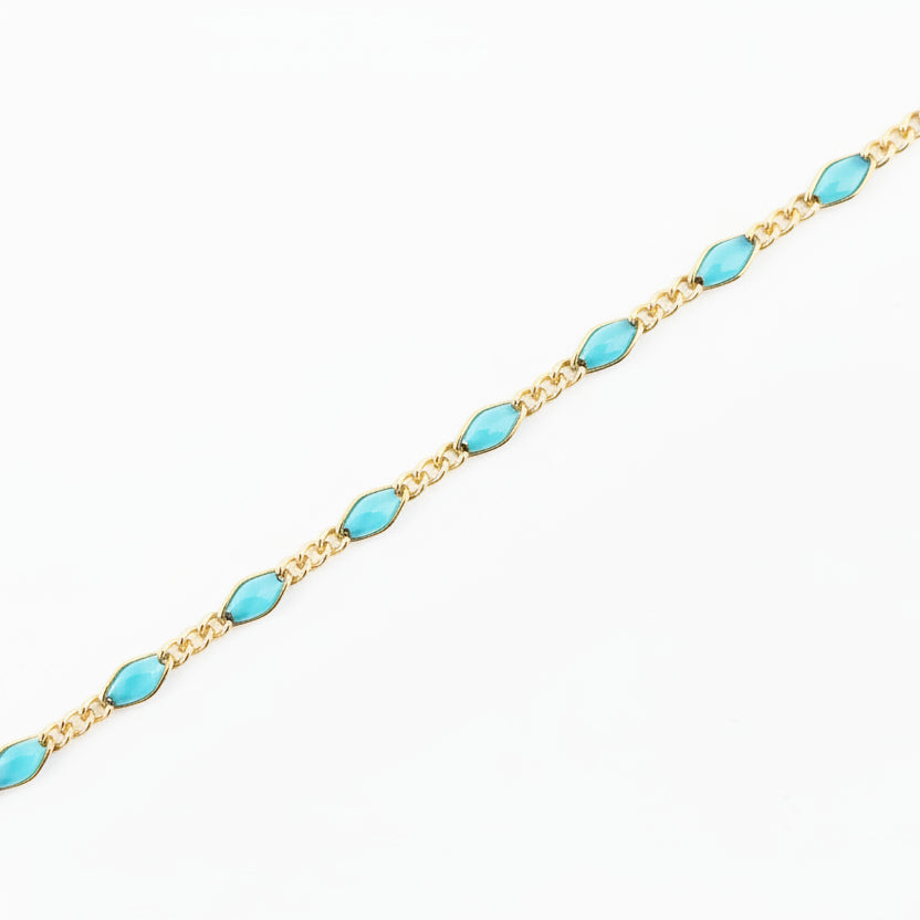 Gold chain with turquoise beads on a light gray background
