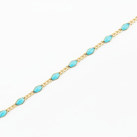 Gold chain with turquoise beads on a light gray background