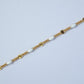 Gold bracelet with white beads on a light gray background