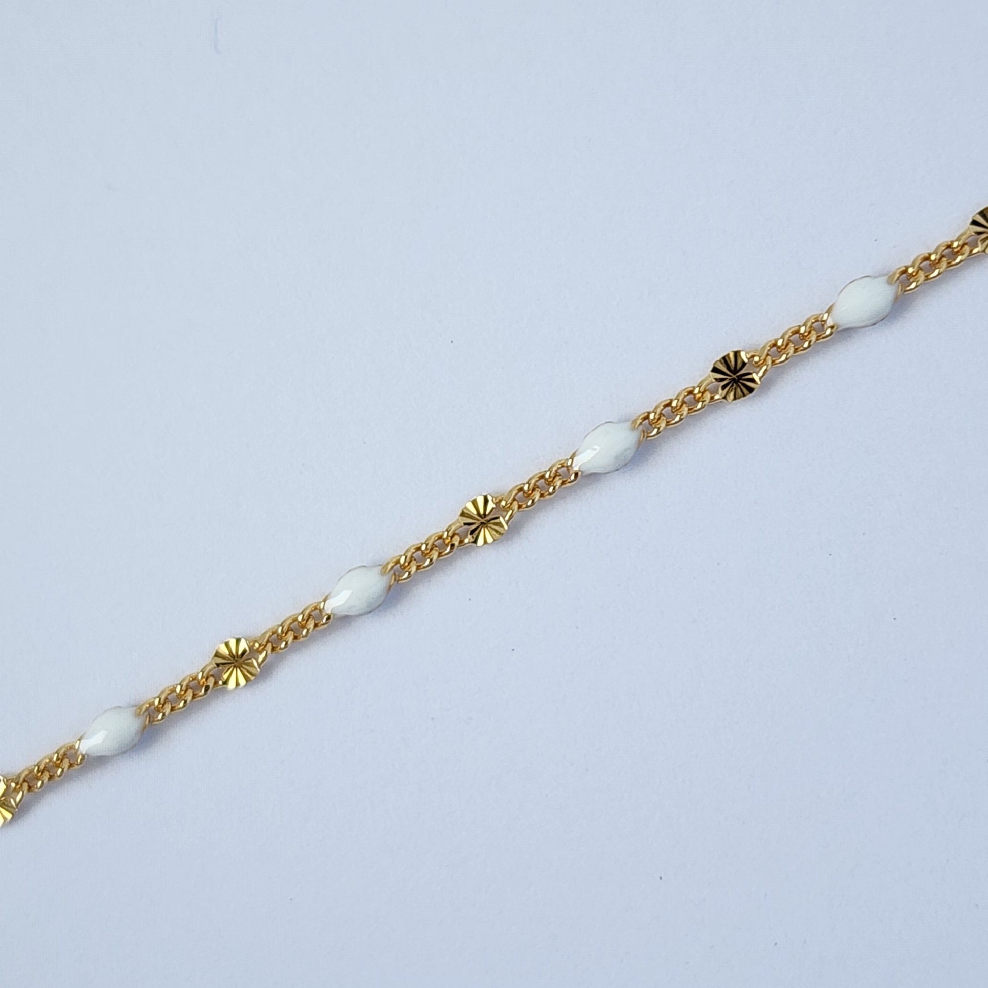 Gold bracelet with white beads on a light gray background