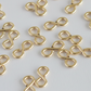 Gold infinity symbol charms scattered on a light gray background