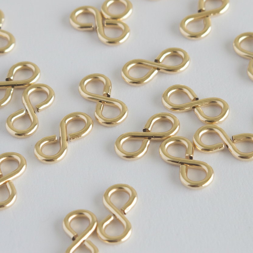 Gold infinity symbol charms scattered on a light gray background