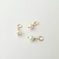 Three pearl charms on gold loops against a white background