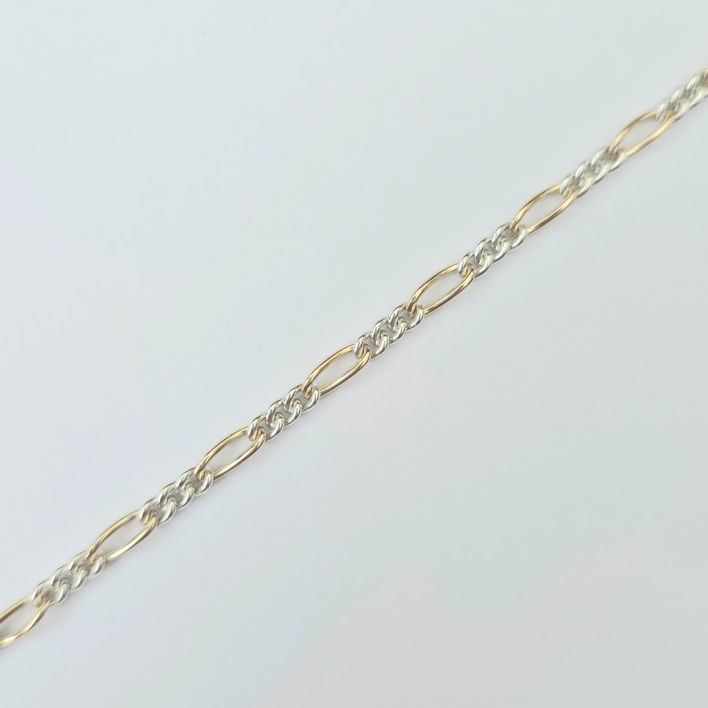 Gold and silver chain on a light gray background