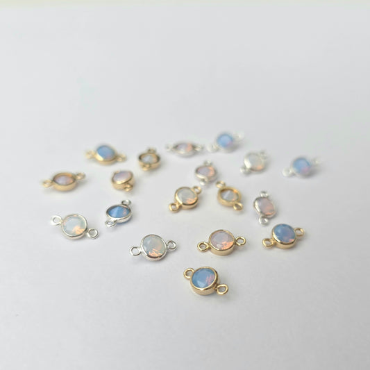 Gold and silver jewelry connectors with gemstones on a light gray background