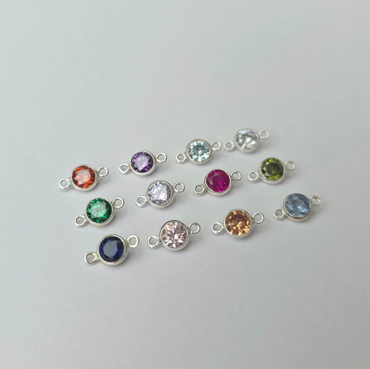 Silver jewelry connectors with colorful gemstones on a light gray background