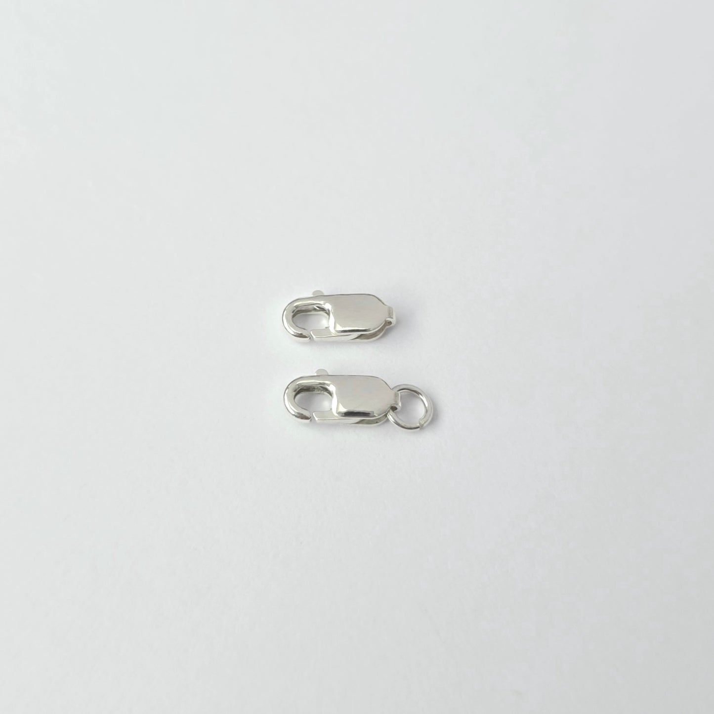 Two silver lobster clasps on a white background