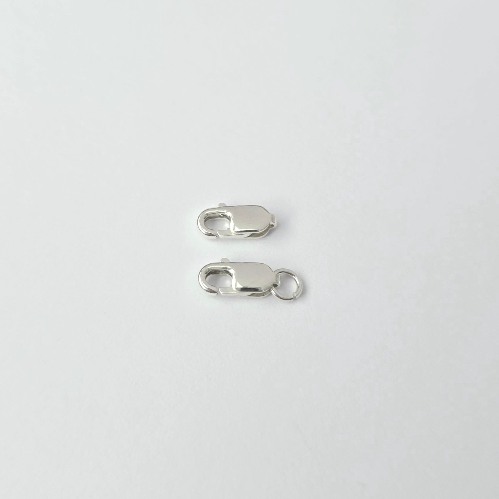 Two silver lobster clasps on a white background