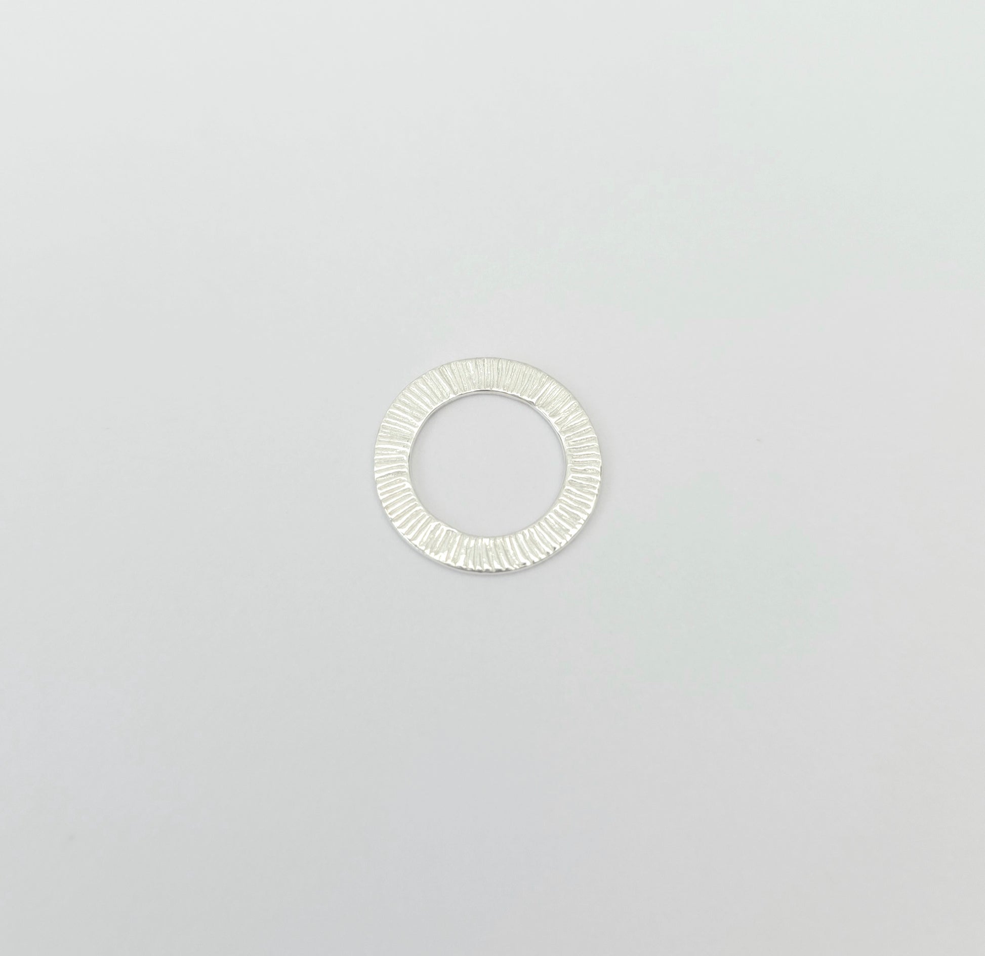 Silver ring with a textured band on a light gray background